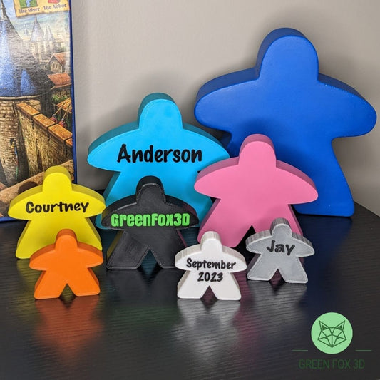 A family of personalized and standard meeples of various colors and sizes.